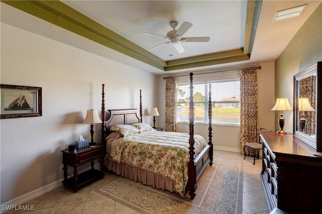 bedroom featuring a tray ceiling, visible vents, baseboards, and light tile patterned floors