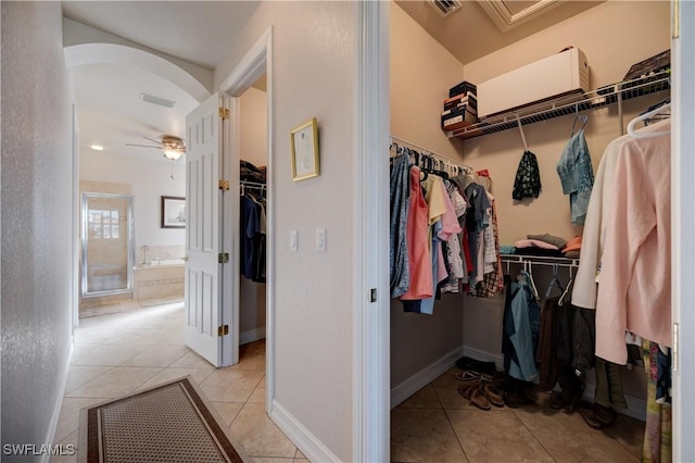 spacious closet featuring arched walkways, ceiling fan, light tile patterned floors, and visible vents