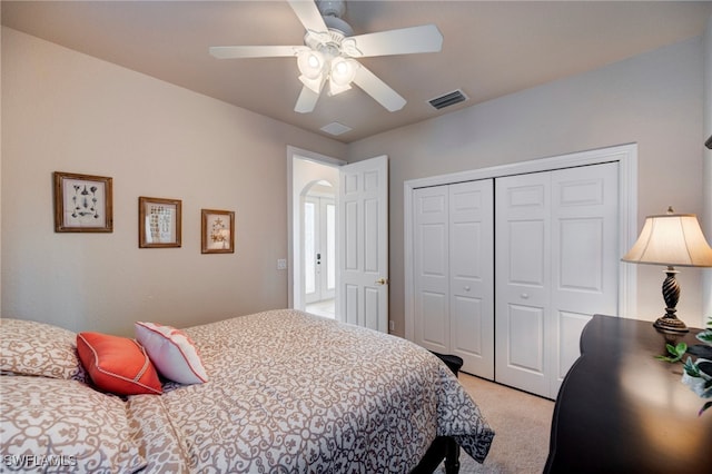 bedroom with visible vents, a closet, a ceiling fan, and light colored carpet