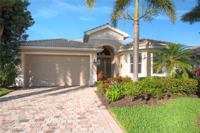 view of front of property with a garage, a tiled roof, decorative driveway, and stucco siding