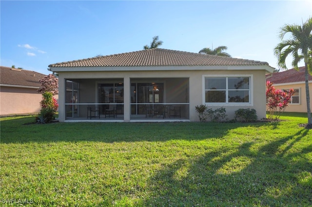 back of property featuring a lawn, a tile roof, a sunroom, and stucco siding