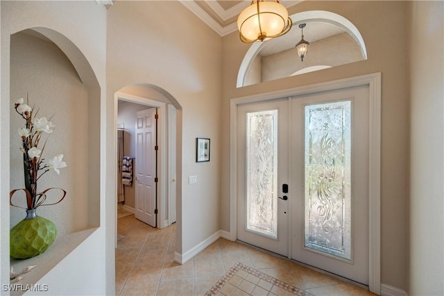 entrance foyer featuring arched walkways, light tile patterned flooring, baseboards, french doors, and crown molding