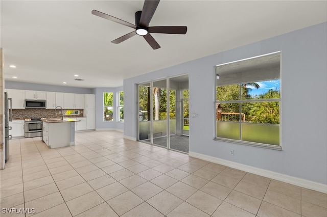 unfurnished living room with light tile patterned flooring, ceiling fan, and sink