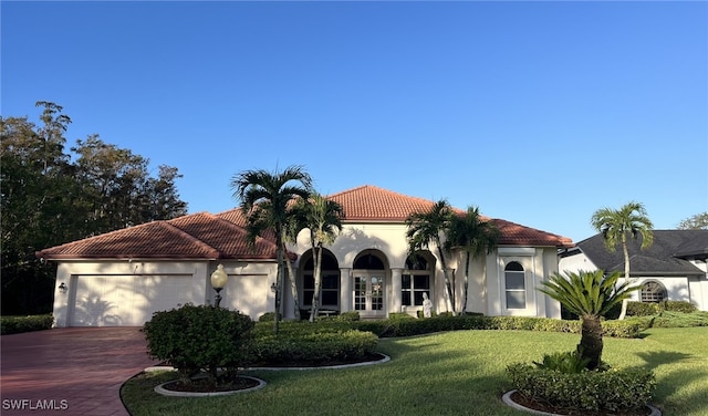 mediterranean / spanish home with a garage and a front lawn