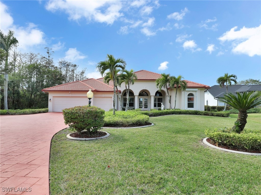 mediterranean / spanish house with a garage and a front lawn