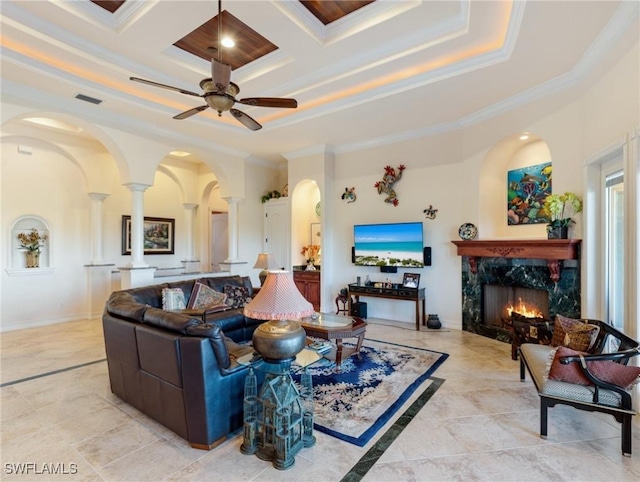 living room featuring a premium fireplace, ornamental molding, coffered ceiling, and ornate columns