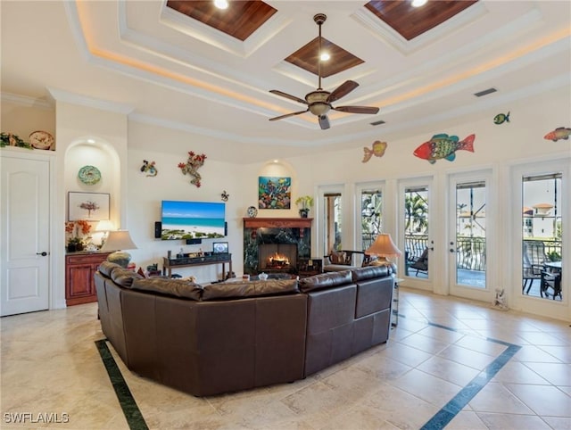 living room with light tile patterned flooring, crown molding, coffered ceiling, ceiling fan, and a premium fireplace