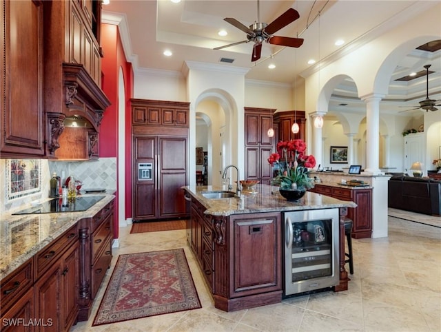 kitchen with an island with sink, sink, wine cooler, paneled built in refrigerator, and black electric cooktop