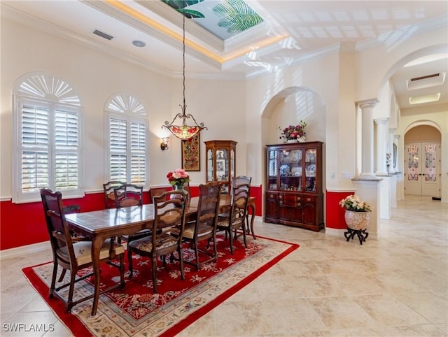 dining area featuring ornamental molding, a tray ceiling, decorative columns, and a high ceiling