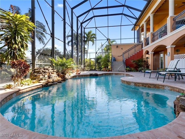 view of swimming pool featuring ceiling fan, glass enclosure, and a patio