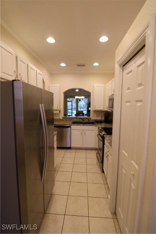 kitchen featuring sink, white cabinetry, light tile patterned floors, ornamental molding, and appliances with stainless steel finishes