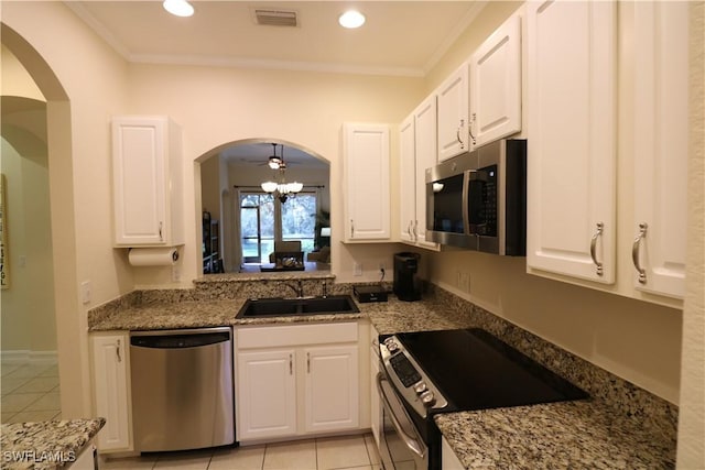 kitchen featuring white cabinetry, dark stone countertops, ornamental molding, light tile patterned floors, and stainless steel appliances