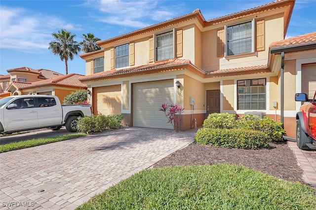 view of front of house featuring a tiled roof, decorative driveway, an attached garage, and stucco siding