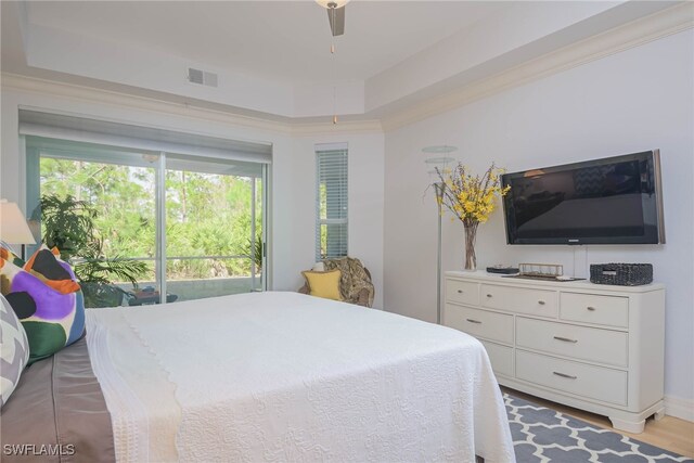 bedroom with hardwood / wood-style flooring, ornamental molding, a raised ceiling, and ceiling fan