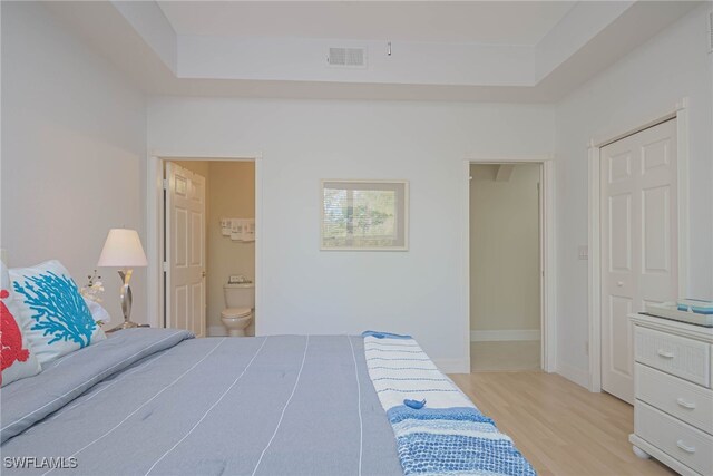 bedroom with ensuite bath and light hardwood / wood-style flooring