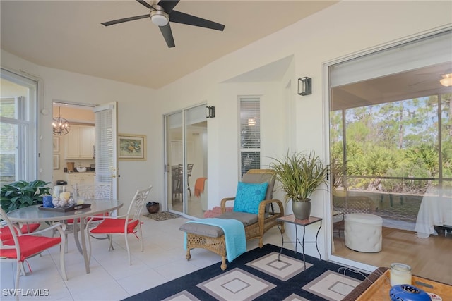 sunroom featuring ceiling fan with notable chandelier