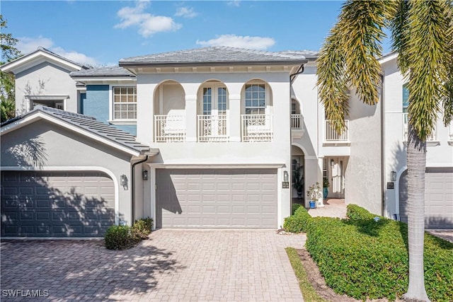 view of front of property featuring a balcony, decorative driveway, and stucco siding