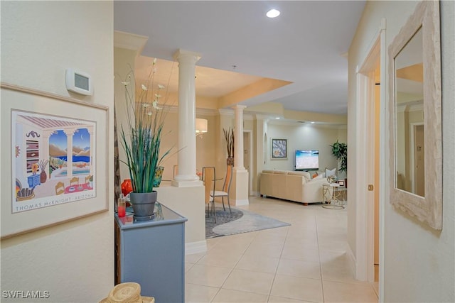 hallway featuring a tray ceiling, recessed lighting, light tile patterned floors, baseboards, and ornate columns