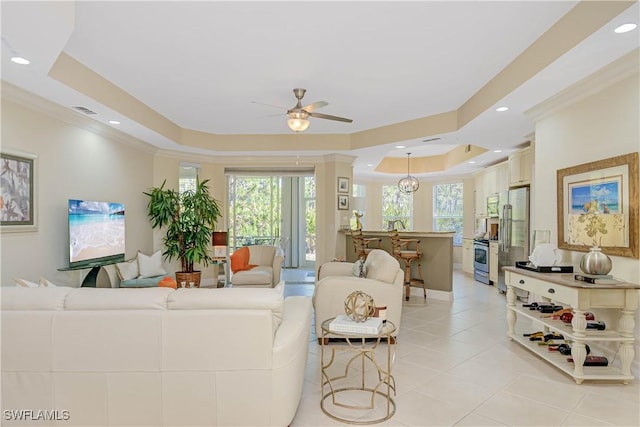 living area with light tile patterned floors, a tray ceiling, a healthy amount of sunlight, and crown molding