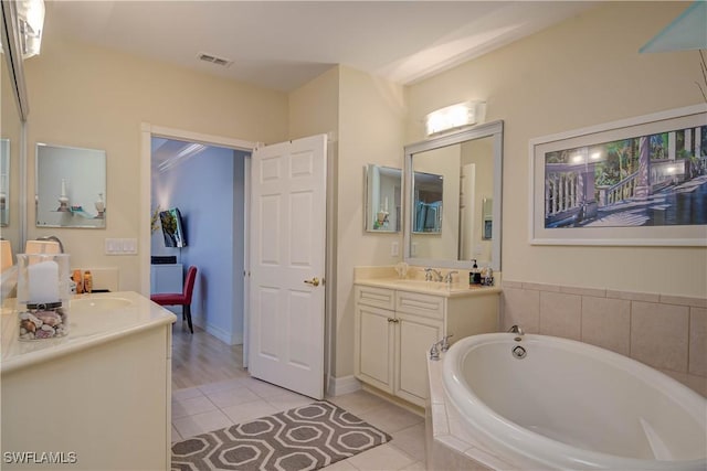 full bathroom featuring visible vents, two vanities, a bath, and tile patterned flooring