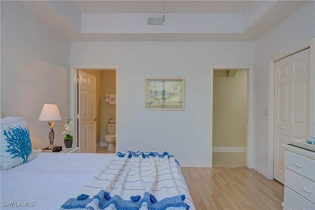 bedroom featuring visible vents, ensuite bathroom, light wood-type flooring, and baseboards