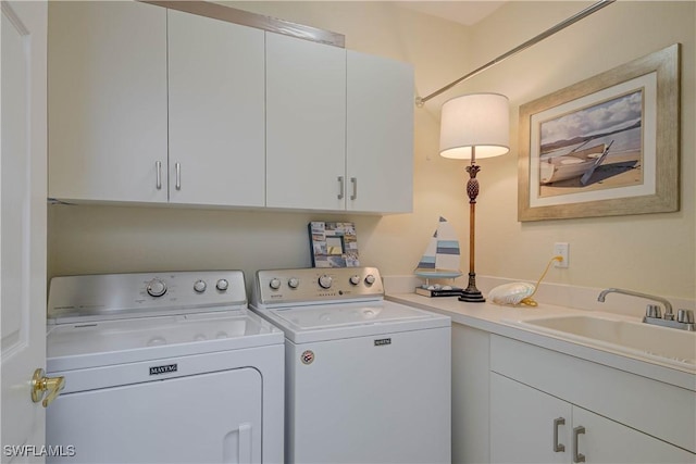 laundry room featuring washing machine and clothes dryer, cabinet space, and a sink