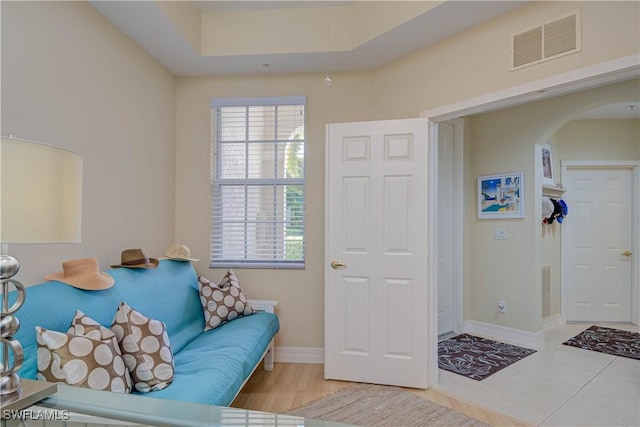 sitting room featuring tile patterned floors, visible vents, arched walkways, baseboards, and attic access