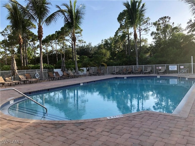 community pool with a patio area and fence