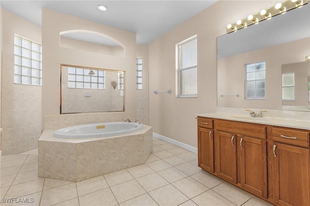 bathroom with tile patterned flooring, vanity, and tiled bath