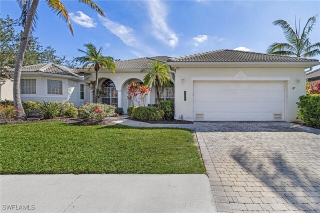 mediterranean / spanish house with a garage and a front lawn