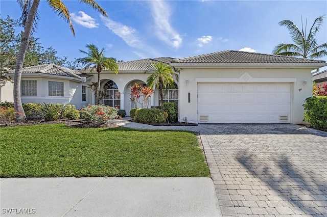 view of front of house with an attached garage, stucco siding, decorative driveway, and a tiled roof