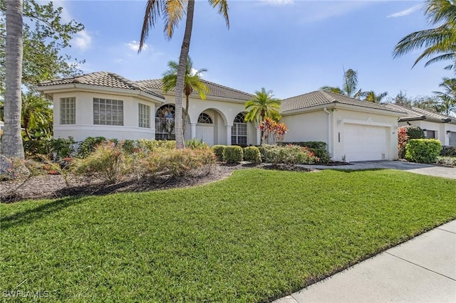 mediterranean / spanish house with an attached garage, a tiled roof, concrete driveway, stucco siding, and a front yard