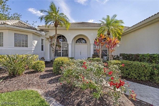 property entrance featuring a tile roof and stucco siding