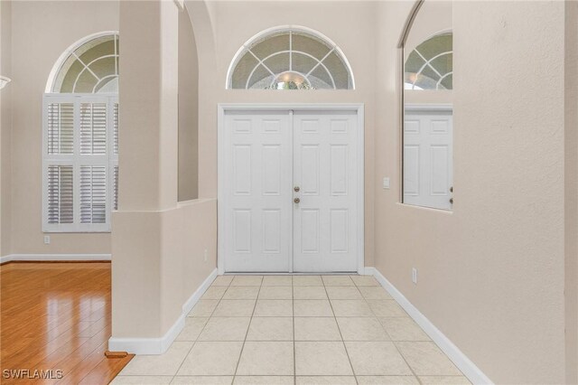 entryway with a high ceiling, baseboards, and light tile patterned floors