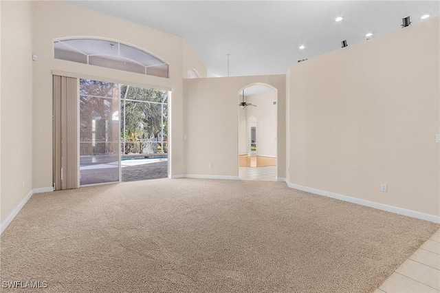 unfurnished living room with arched walkways, baseboards, a towering ceiling, ceiling fan, and carpet