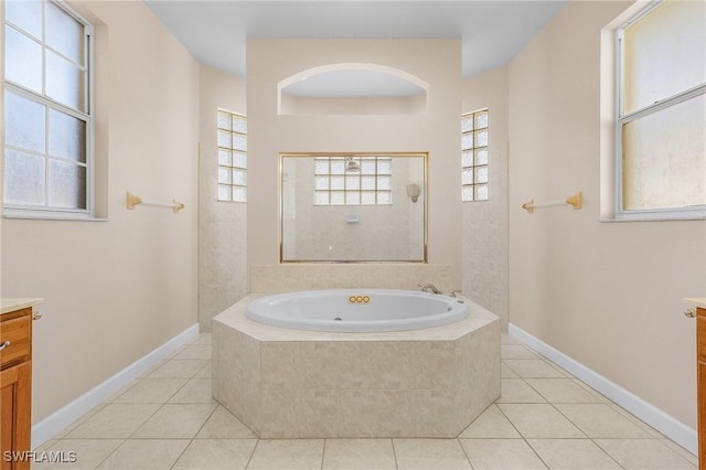 bathroom with a garden tub, tile patterned floors, vanity, baseboards, and walk in shower