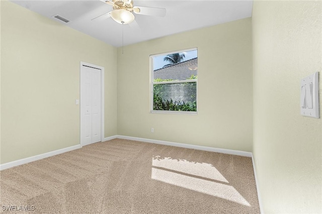 spare room with ceiling fan, carpet flooring, visible vents, and baseboards