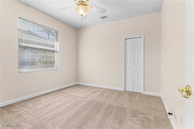 carpeted spare room featuring a ceiling fan, visible vents, and baseboards