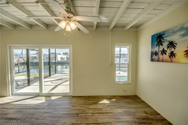 unfurnished room with hardwood / wood-style floors, ceiling fan, beamed ceiling, and a water view