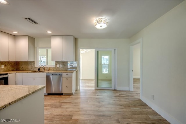 kitchen with sink, stainless steel dishwasher, light stone countertops, decorative backsplash, and white cabinets