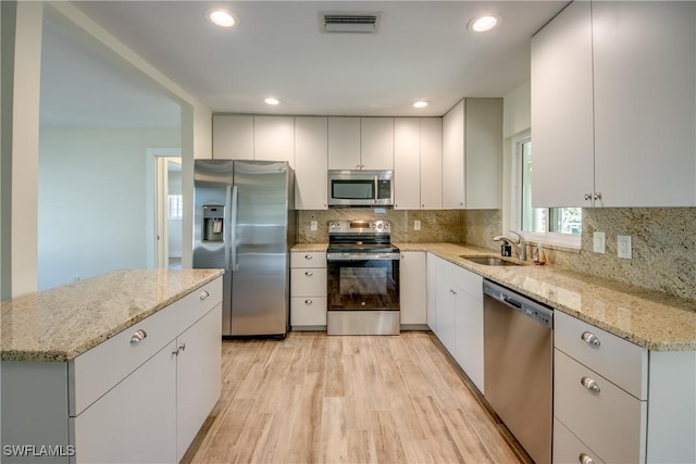 kitchen with light wood-type flooring, stainless steel appliances, sink, and white cabinets