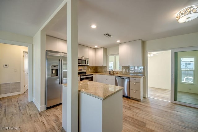 kitchen with sink, light hardwood / wood-style flooring, backsplash, stainless steel appliances, and white cabinets