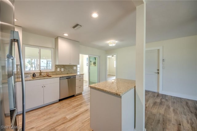 kitchen featuring white cabinetry, appliances with stainless steel finishes, light wood-type flooring, and light stone counters