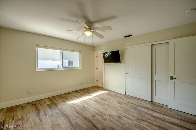 unfurnished bedroom with light hardwood / wood-style flooring, a closet, and ceiling fan