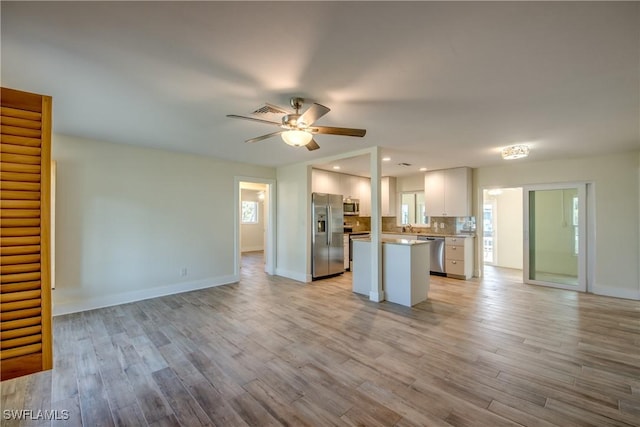 kitchen with white cabinetry, backsplash, ceiling fan, stainless steel appliances, and light hardwood / wood-style flooring