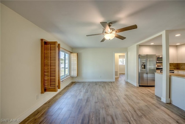 unfurnished living room featuring ceiling fan and light wood-type flooring