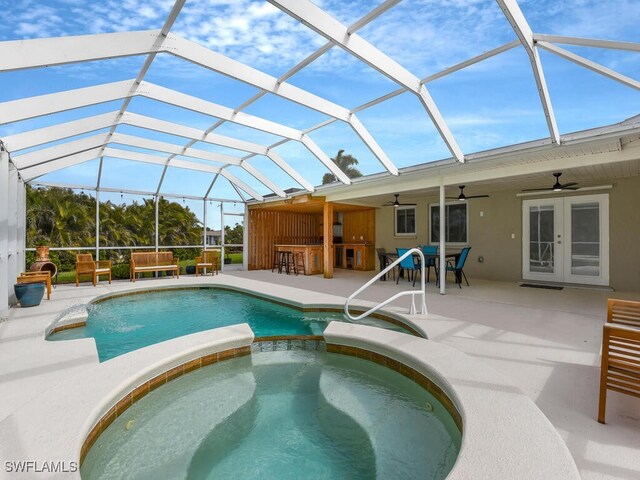 view of swimming pool featuring exterior bar, an in ground hot tub, a lanai, ceiling fan, and a patio area