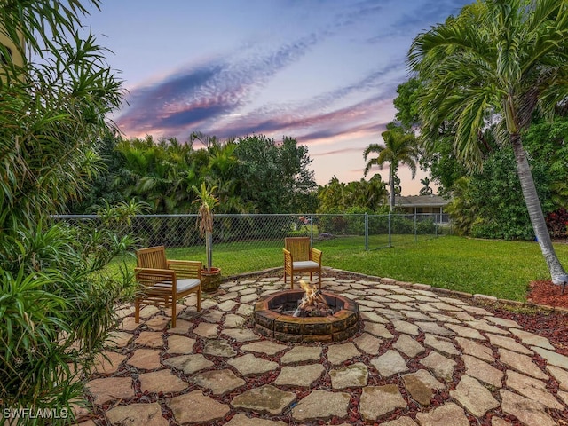 patio terrace at dusk featuring a yard and a fire pit