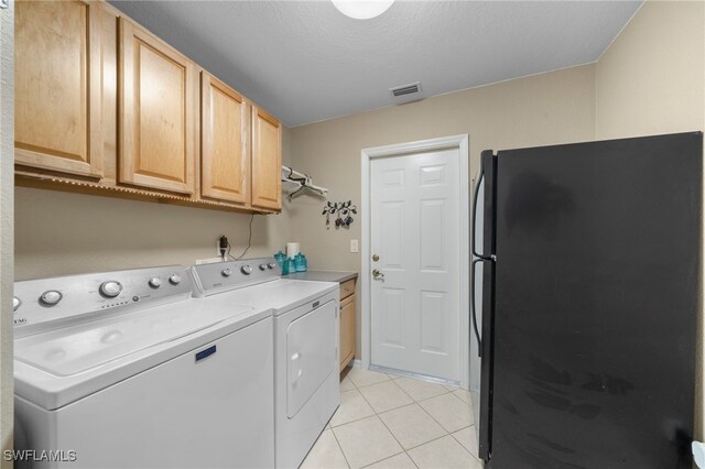 laundry area with light tile patterned flooring, cabinets, washing machine and dryer, and a textured ceiling