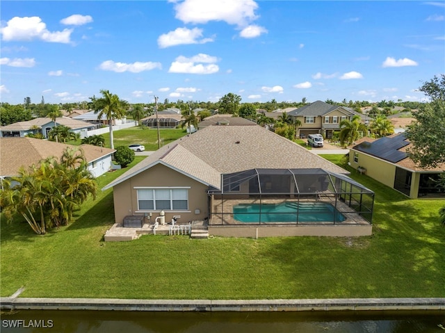 back of property with a patio, a water view, a yard, and glass enclosure